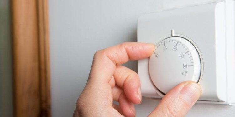 48146048 - close up of female hand on central heating thermostat