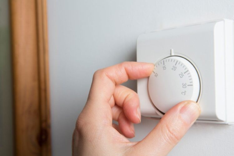 48146048 - close up of female hand on central heating thermostat