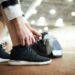 Contemporary sportsman tying shoelaces on sneakers while preparing for training at stadium