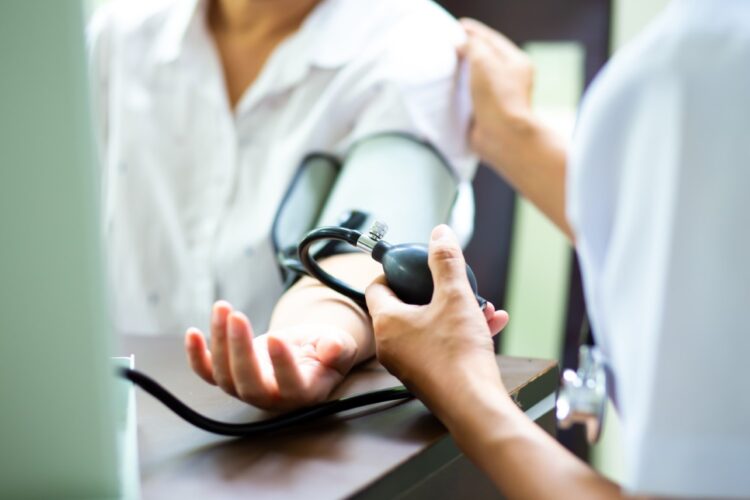Nurse measuring blood pressure of senior woman at home. health insurance concept