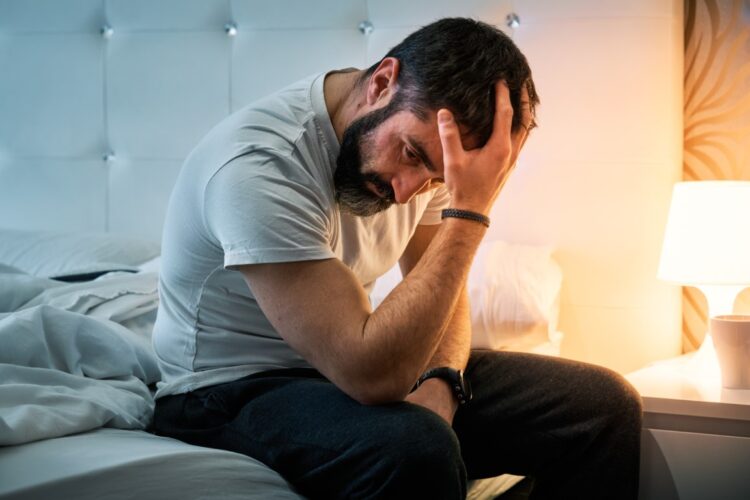person with some kind of problem sitting on the bed and shaking their head while stirring their hair. High quality photo